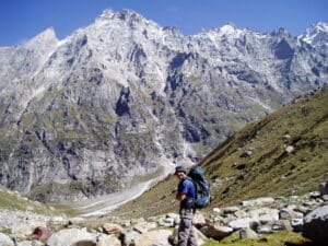 Trekker standing on a rocky path with high snow-covered mountains in the background