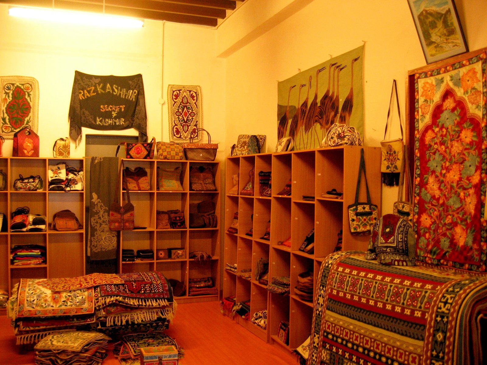 A handicraft shop in Kashmir displaying embroidered bags, rugs, and wall hangings.