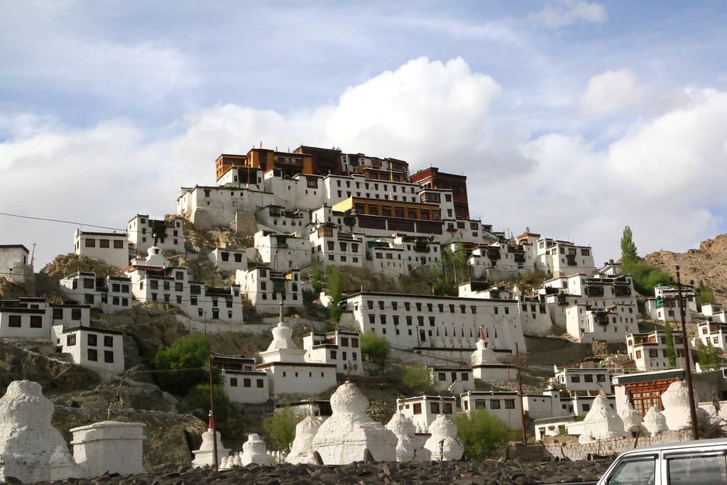 Thiskey Monastery on a hill with white buildings and stupas under a blue sky