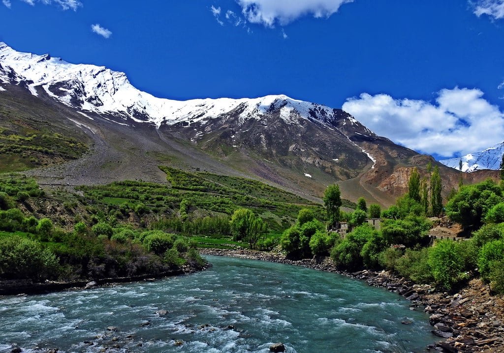 Snow-capped mountains and river flowing through lush green Suru Valley in Ladakh