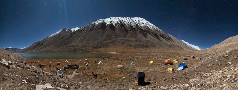Campsite with colorful tents below a snow-covered mountain during the Snow Leopard Trek