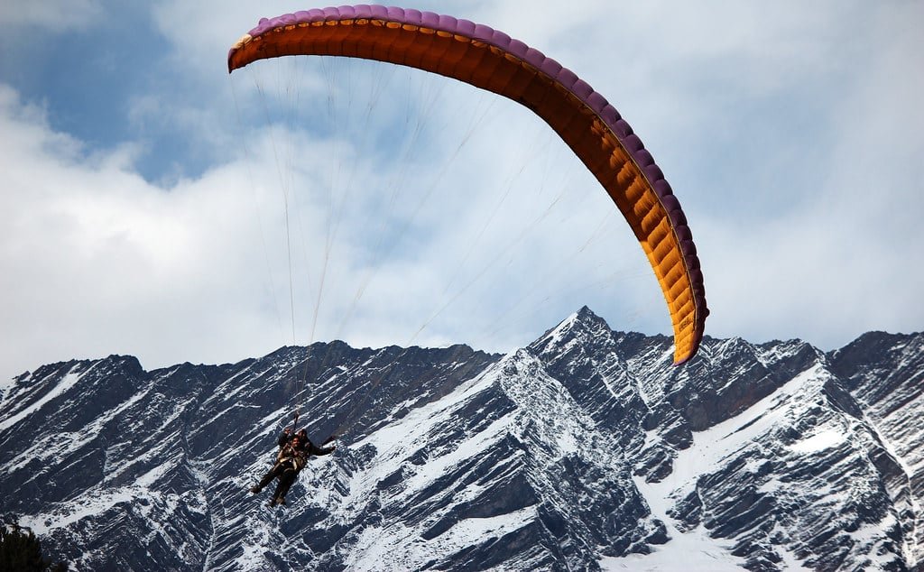 Tourist enjoying tandem paragliding with trainer from a mountain slope
