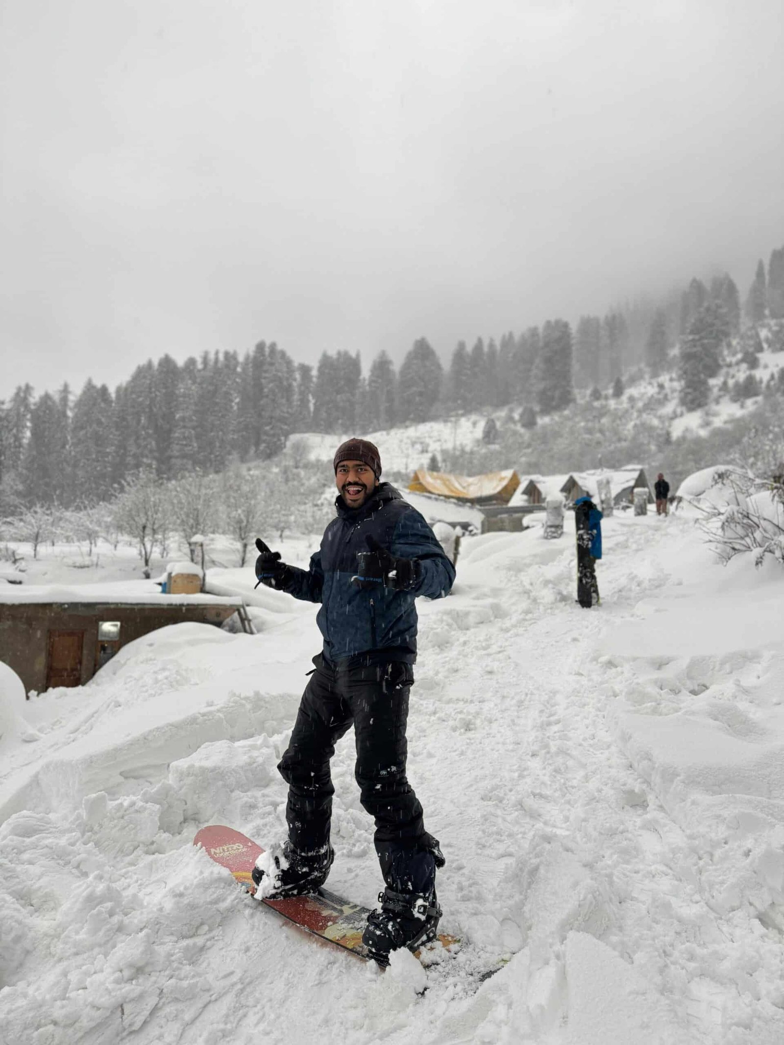 Man snowboarding in a snowy mountain landscape during snowfall