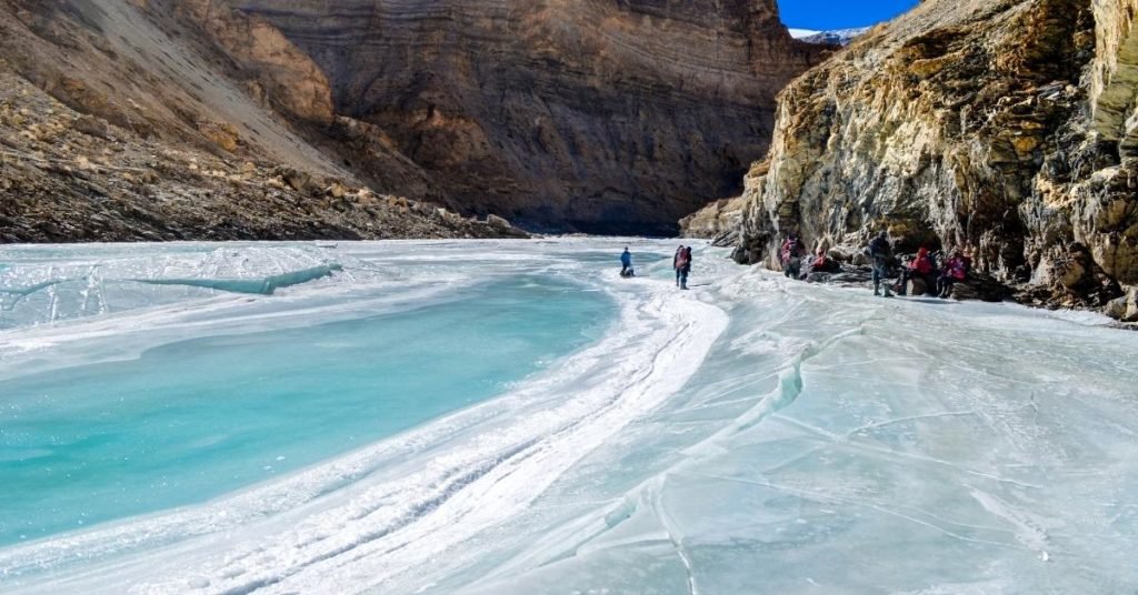 Trekkers walking on the frozen Zanskar River between rocky cliffs during chadar trek