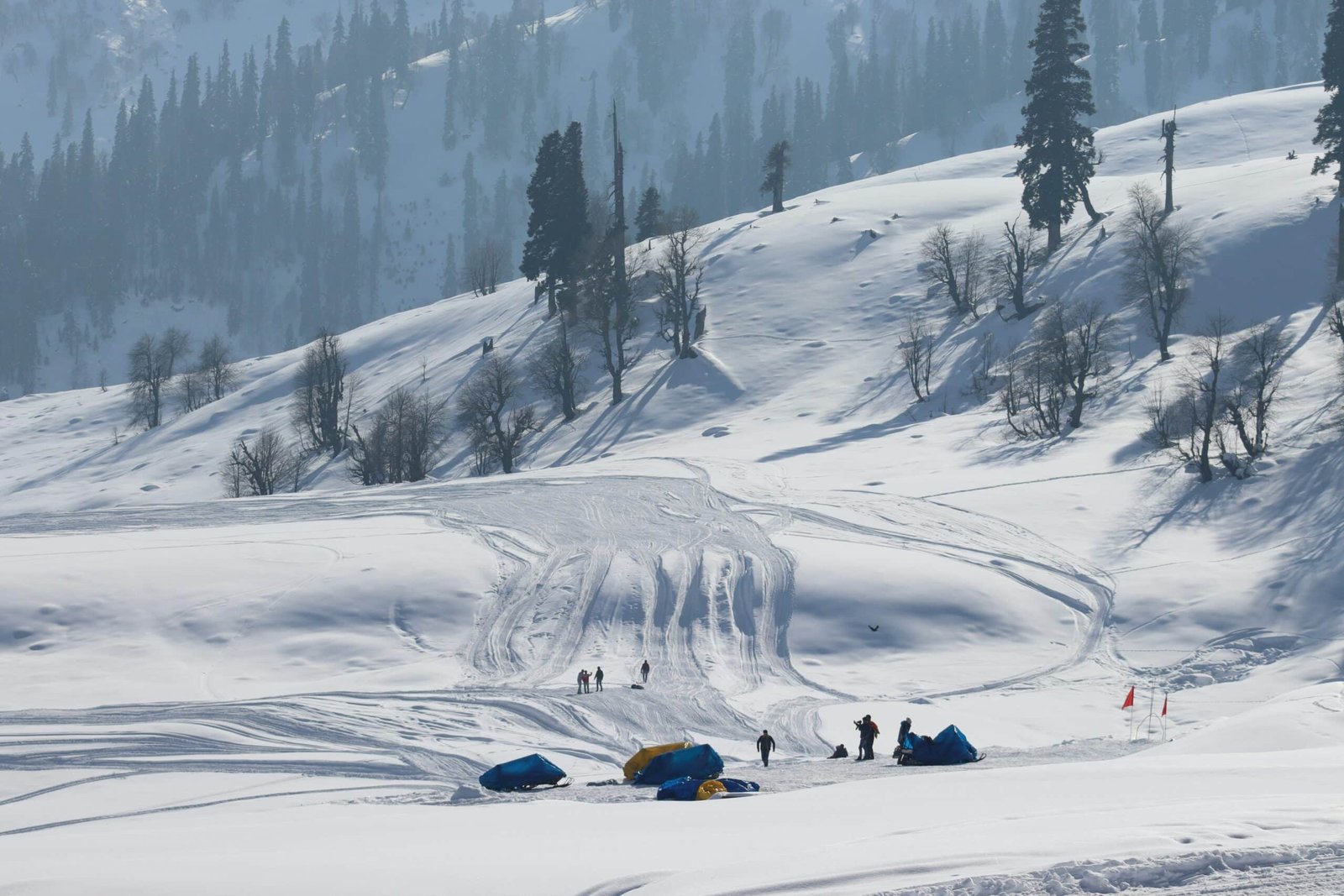 Snow-covered slopes with people and sleds in Gulmarg winter