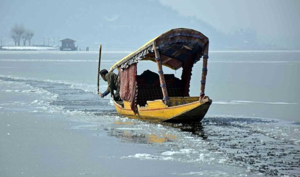 Man rowing a boat through frozen dal lake in srinagar