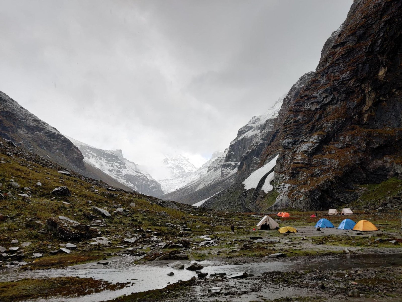 Trekkers are camping at a flat surface between the mountains 
