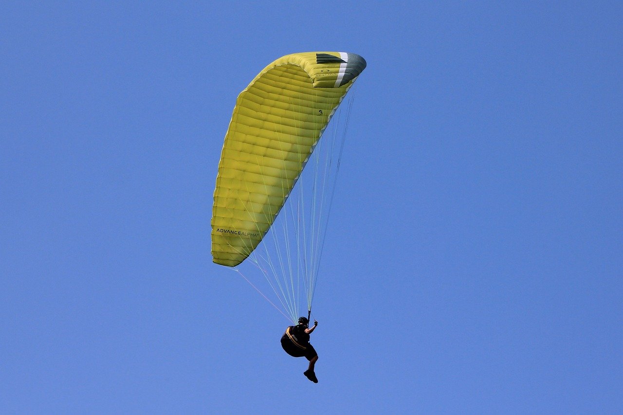 Solo paraglider flying under a yellow canopy in srinagar