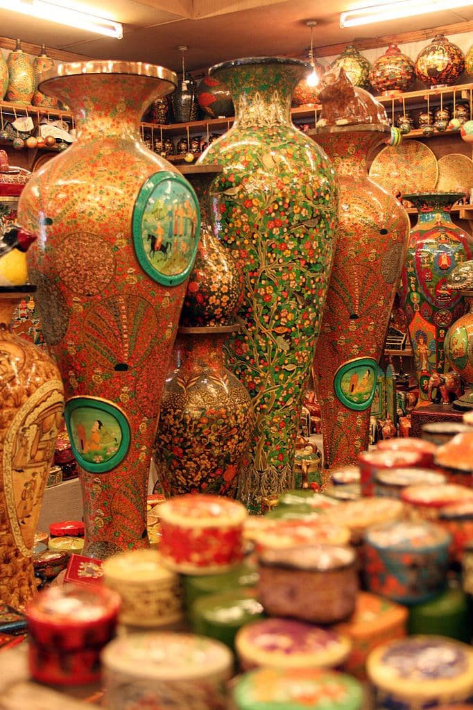 Colorful display of large hand-painted Kashmiri papier-mâché vases and intricately decorated boxes in a traditional craft shop