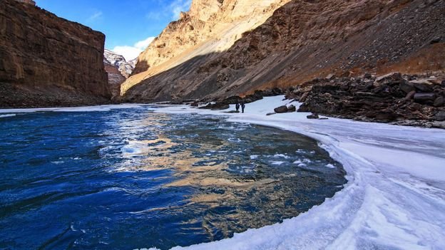 Partially frozen river flowing through rocky mountains in Ladakh