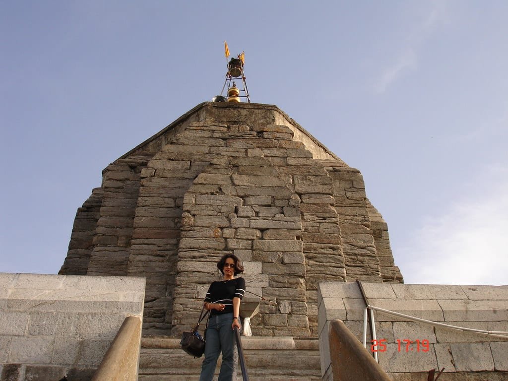 a girl is posing for a picture on the stairs of Shankaracharya temple