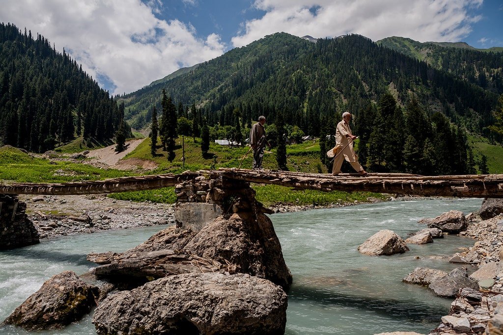 A man is crossing the river with the help of a bridge in Sarbal village.
