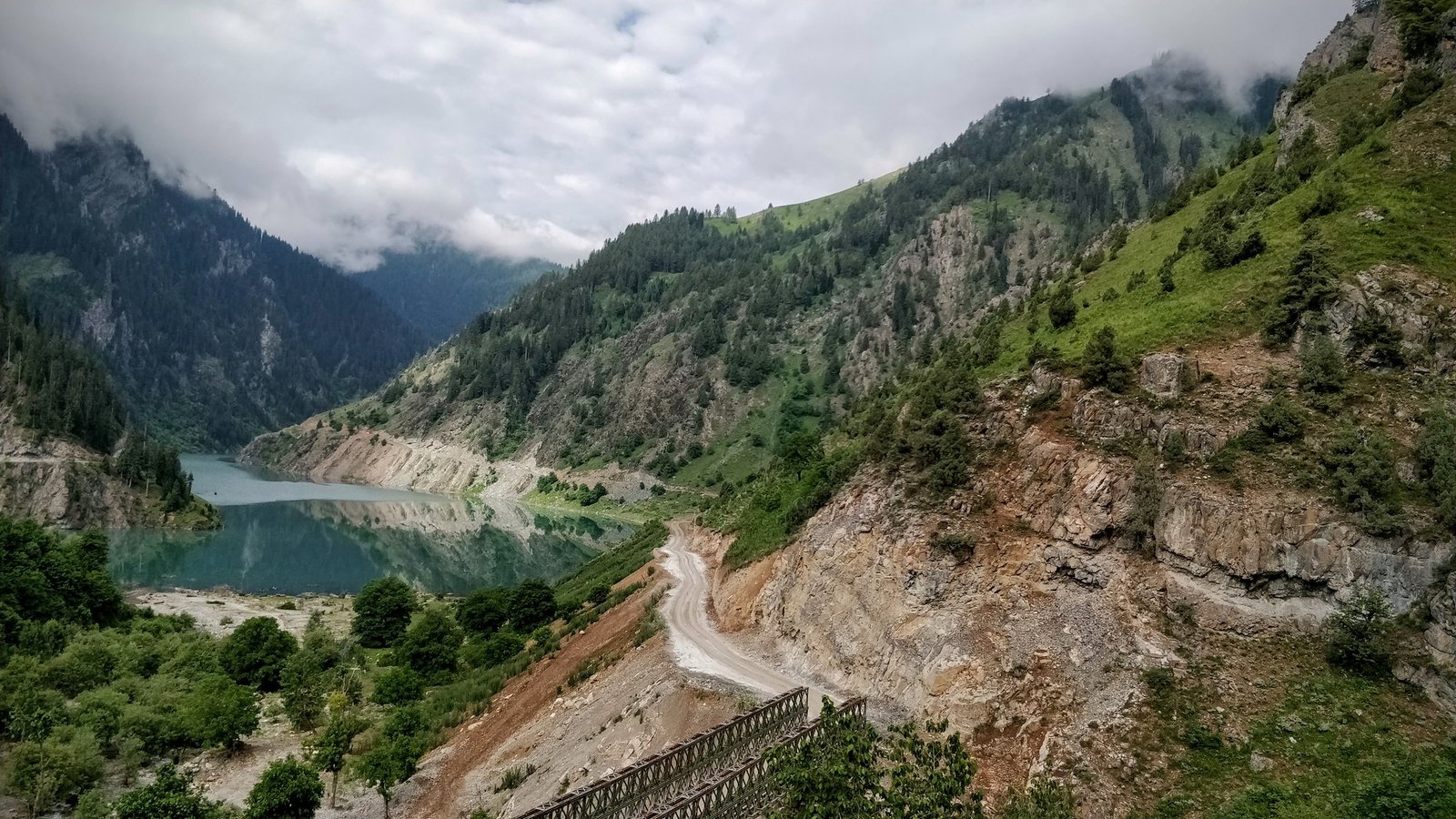 Mountain lake surrounded by rocky hills and greenery under cloudy sky in bangus valley