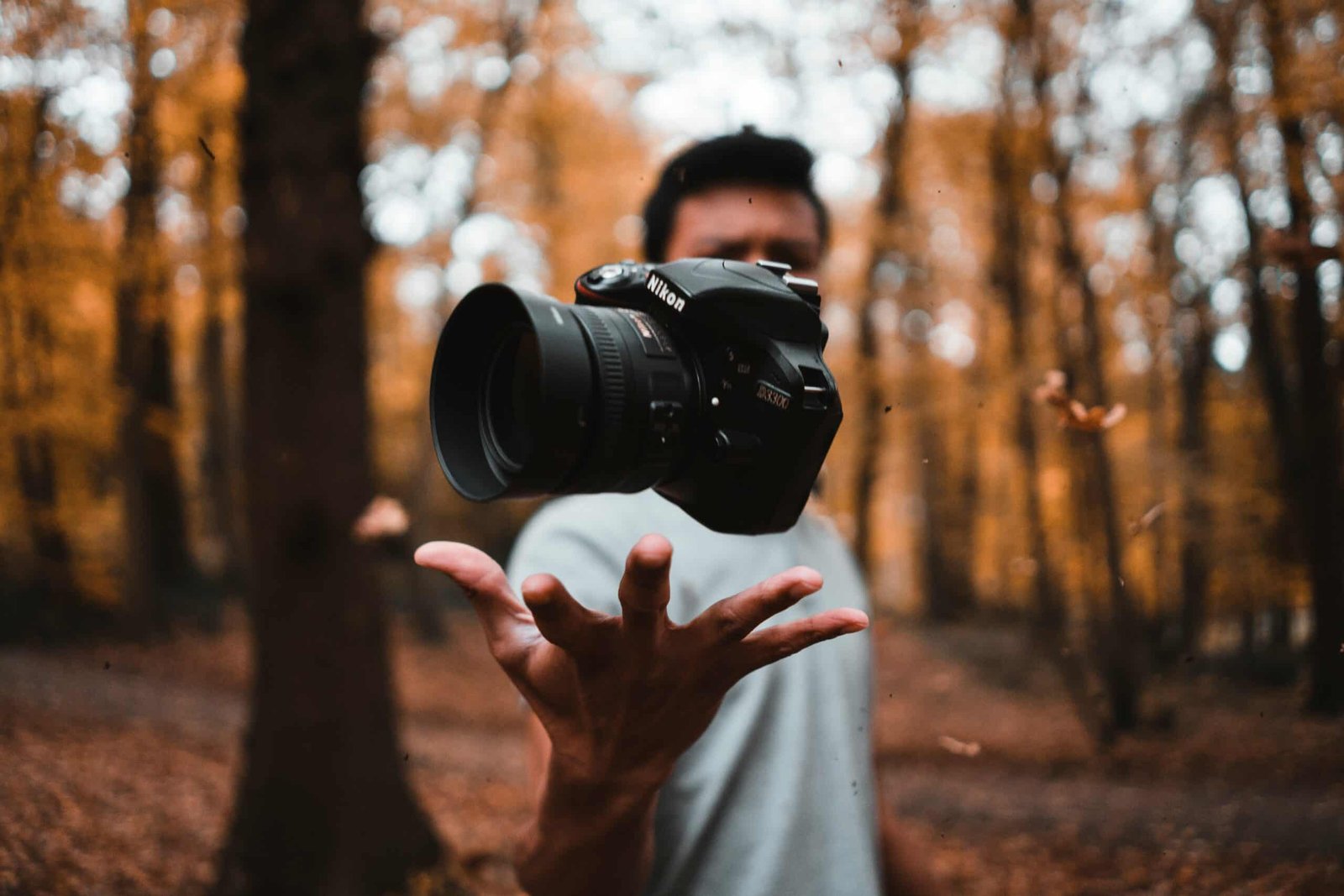 Person tossing a Nikon camera in a forest of srinagar