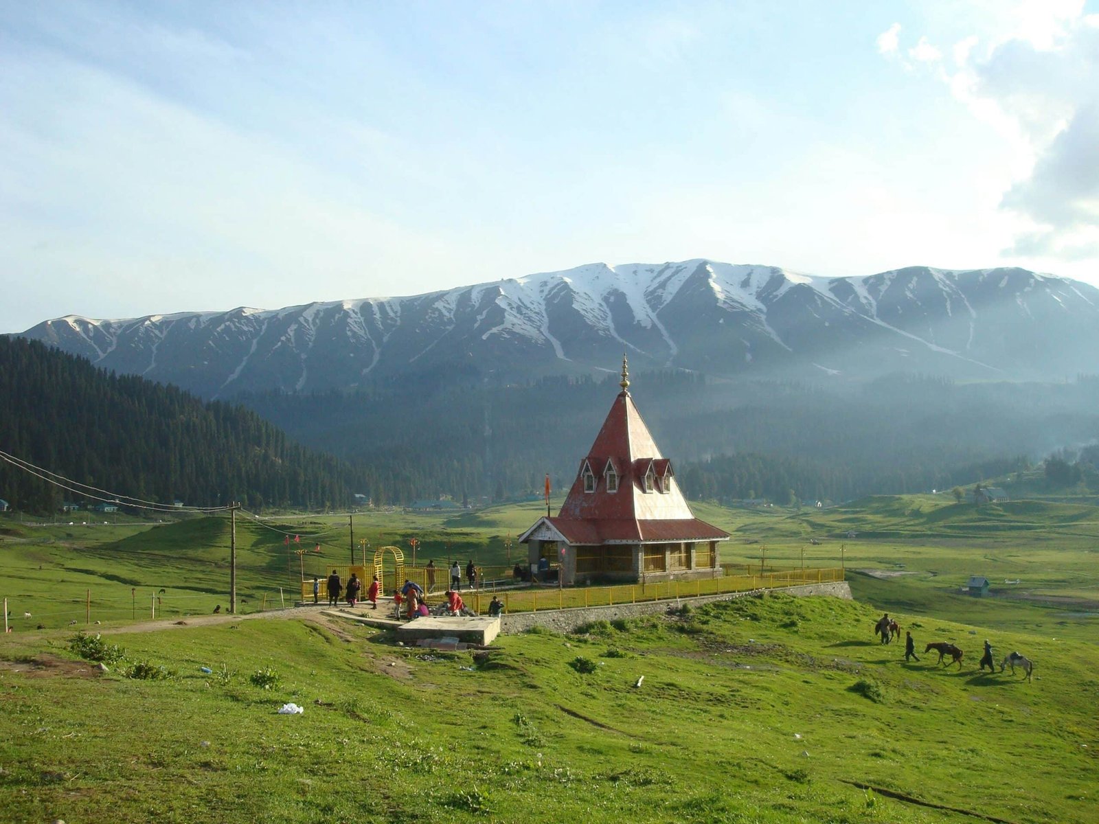 Temple on a green meadow with snow-capped mountains in the background