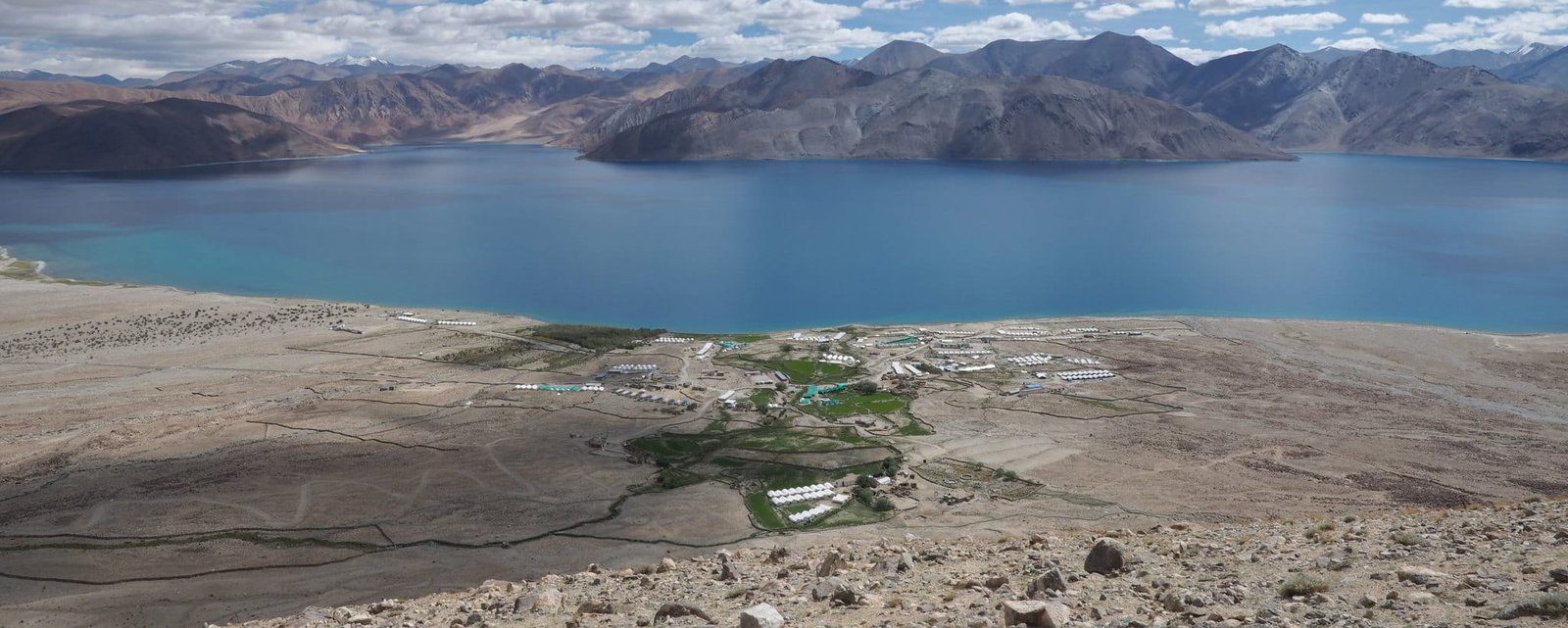 Aerial view of Pangong Lake with turquoise waters, surrounded by barren mountains