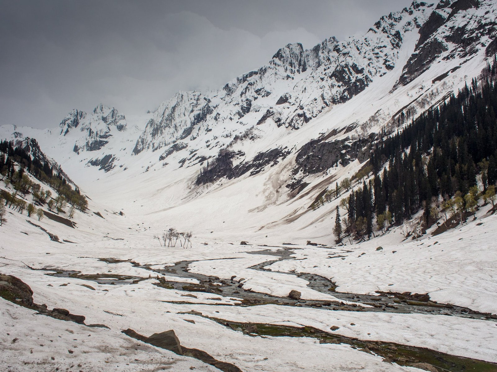 Snow-covered Thajiwas Glacier valley in kashmir with a stream running through and mountains in the background