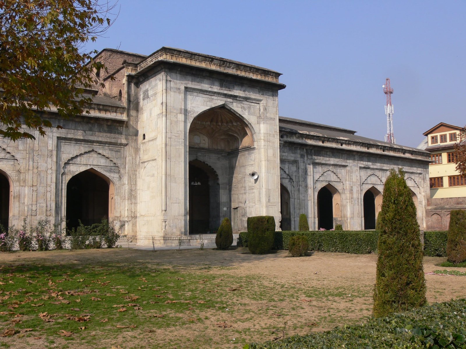 Stone mosque with Mughal-style arches and trimmed garden in front
