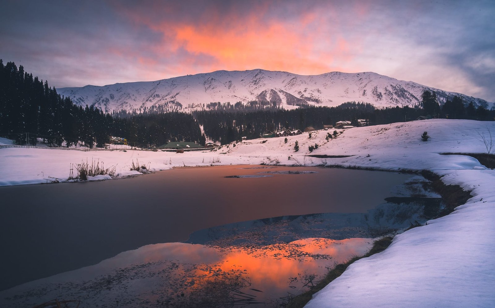 Snowy sunset view in Gulmarg, Kashmir with a frozen lake and pine trees