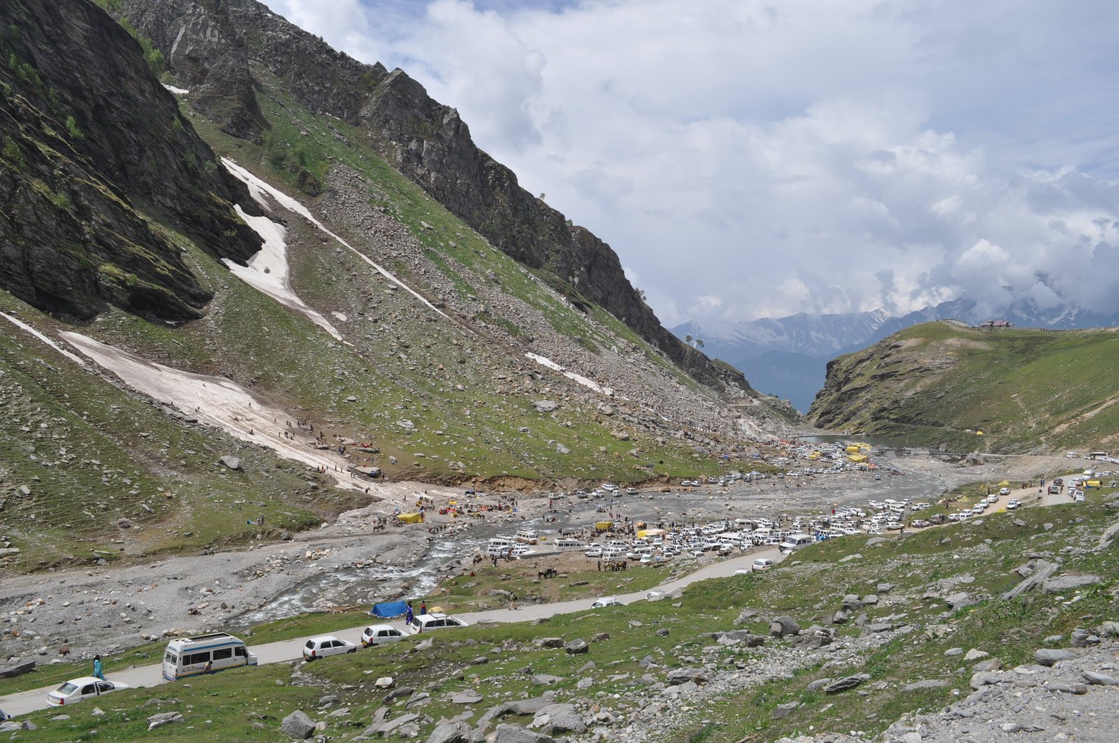 Vehicles and tourists at Rohtang Pass surrounded by green mountains