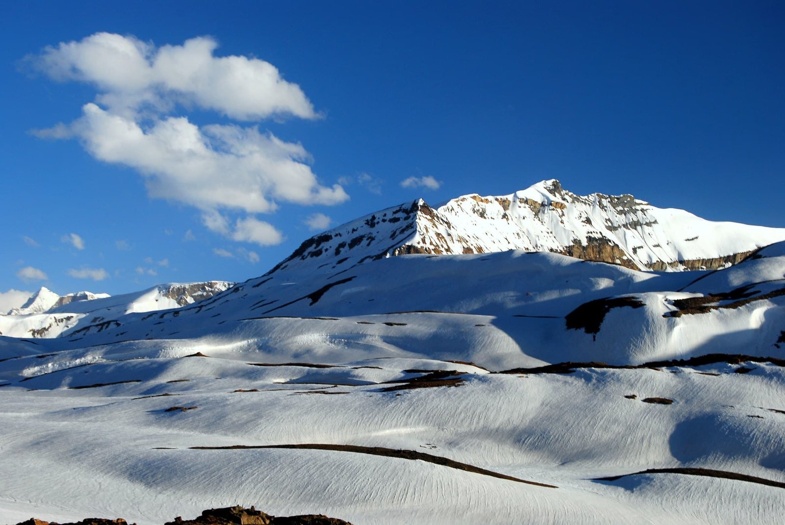 Snow-covered Bara-Lacha La Pass under a deep blue sky with scattered clouds