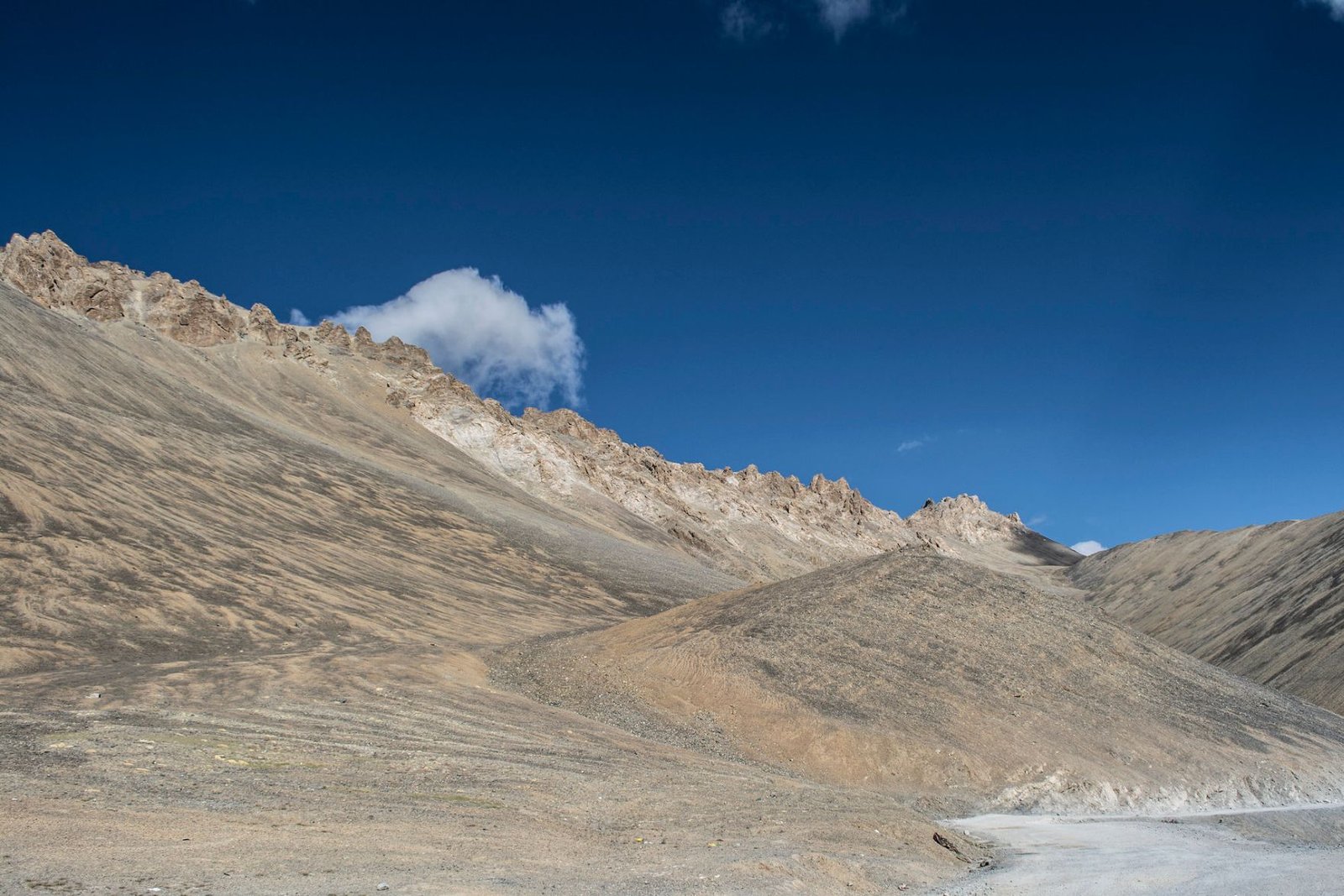 Barren brown hills at Lachulung La Pass under a clear deep blue sky