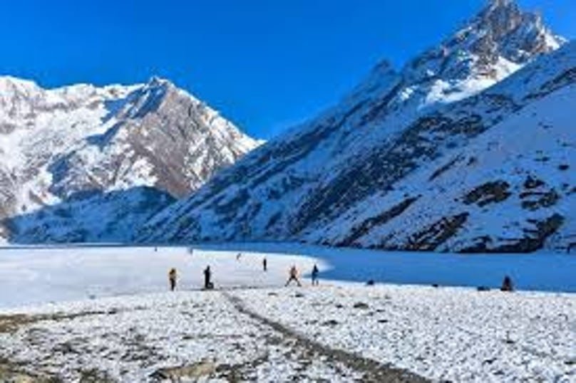 Frozen lake in yusmarg surrounded by snowy mountains with people walking on the ice
