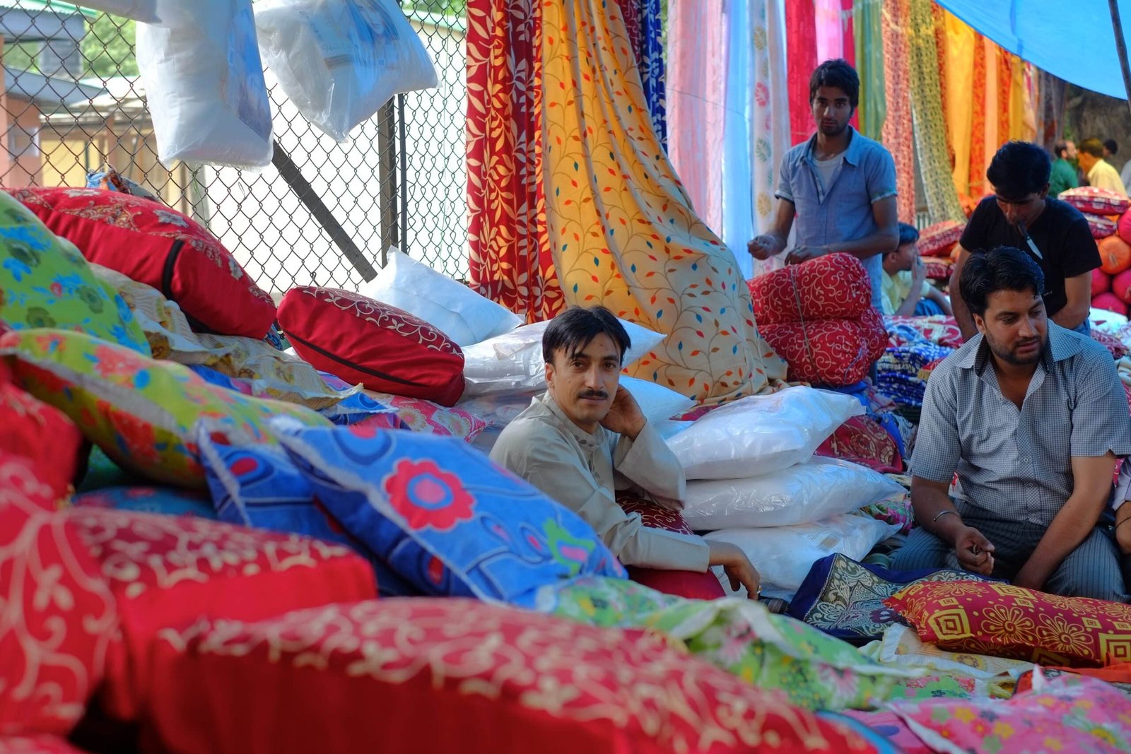 Men selling colorful cushions and fabrics at a market stall oin pahalgam, kashmir