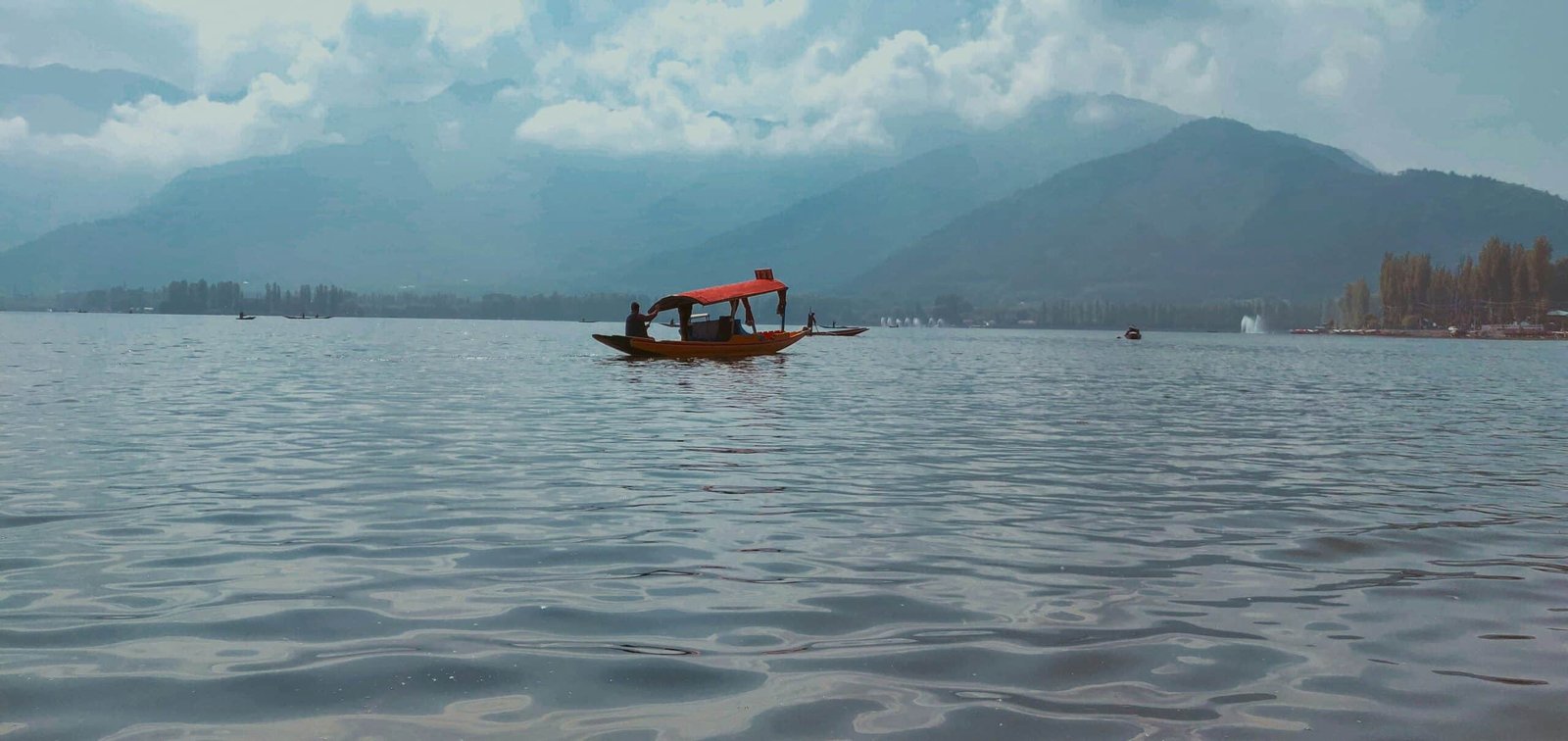 Wooden boat with red canopy on a calm dal lake in srinagar