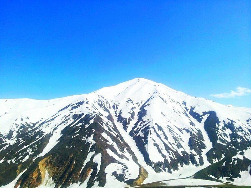 Snow-covered mountain peak under a clear blue sky at Peer Ki Gali