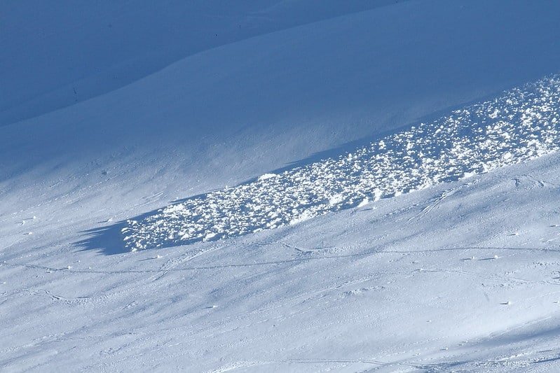 Small snow avalanche path with scattered snow chunks