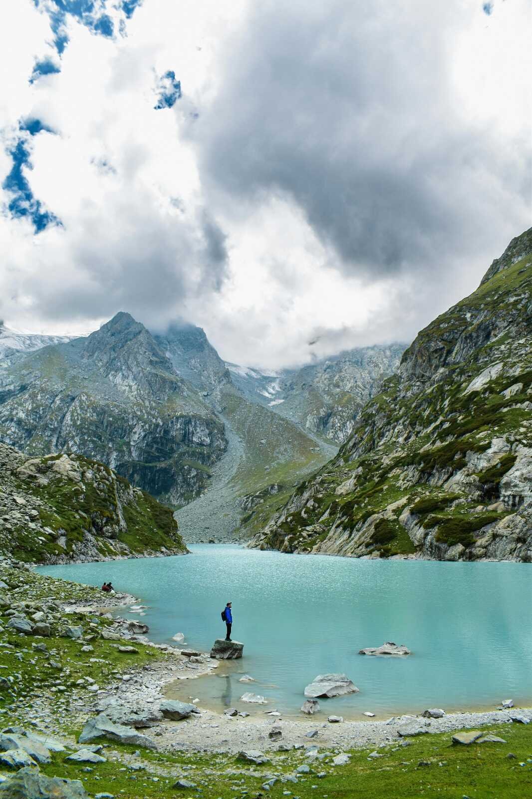 Turquoise lake in Pahalgam with a person standing on a rock