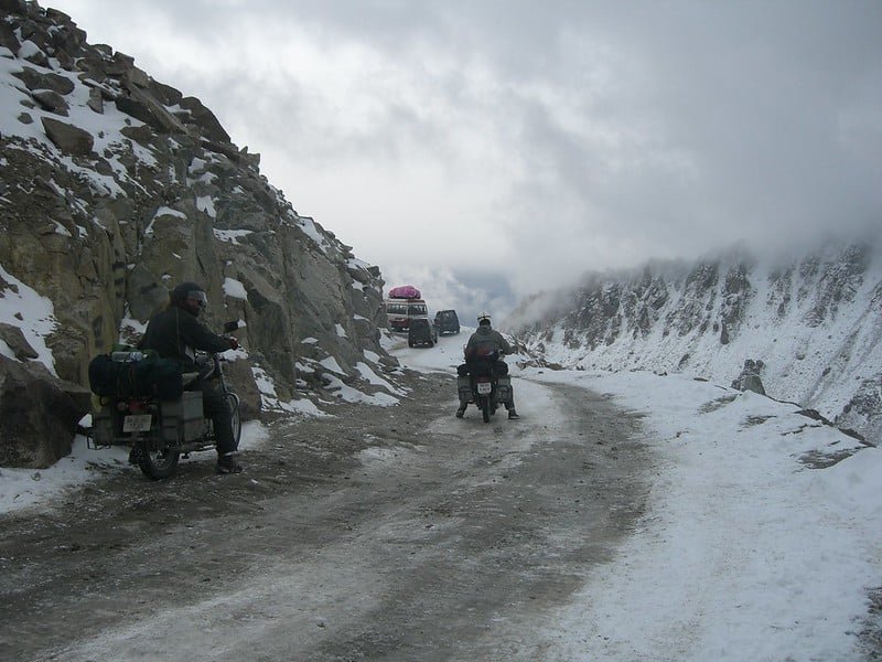 Bikers riding through a snowy mountain pass near Leh