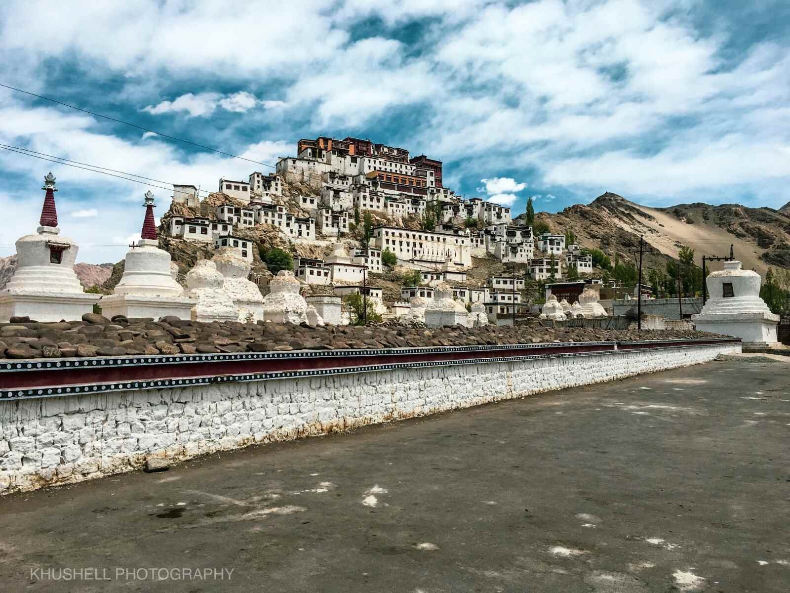 Hilltop monastery with white stupas and surrounding buildings