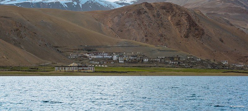 Distant view of Sumur Village nestled in the brown mountains with a lake in the foreground in nubra valley