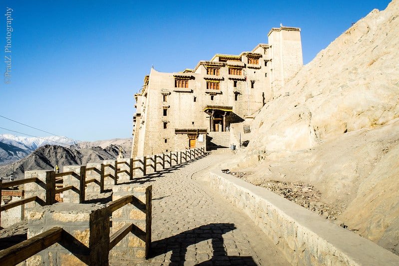 Leh Palace under clear blue sky with a stone pathway leading up to it