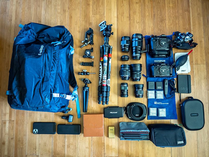 Photography gear flat lay with cameras, lenses, tripods, and a backpack