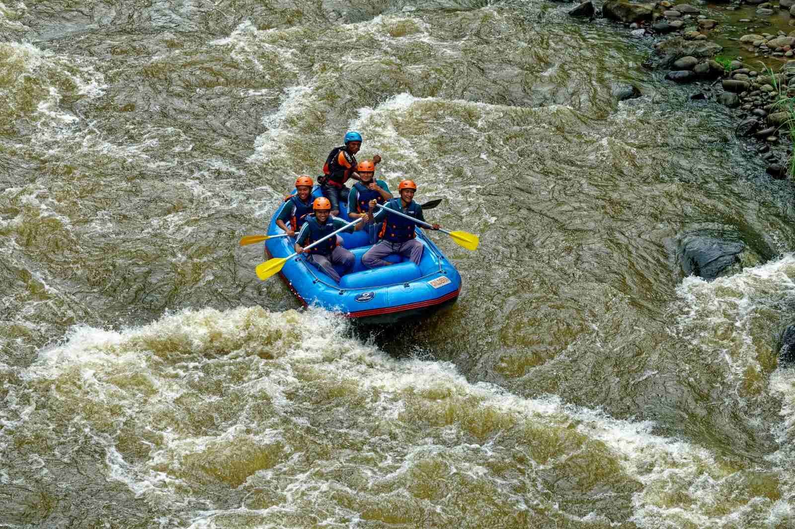 People rafting in a blue boat on a fast river in ladakh