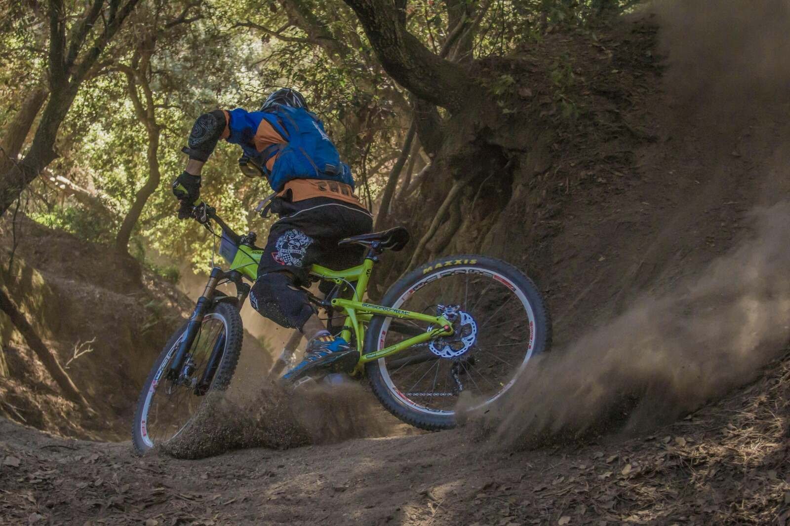 Mountain biker kicking up dust while turning on a forest trail