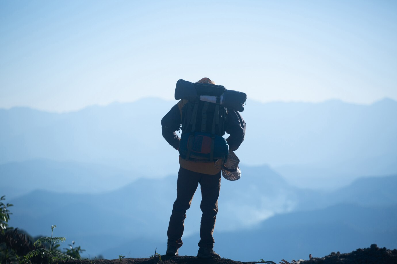 Trekker with a backpack looking at distant mountain ranges from panikhar