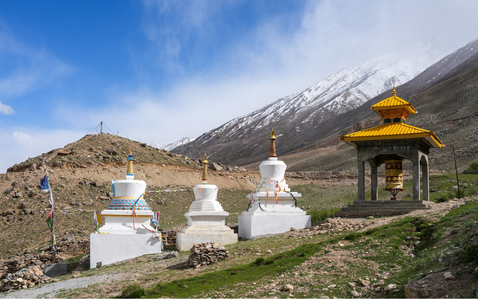 Three white stupas and a prayer wheel at Stakrimo Gompa in Padum