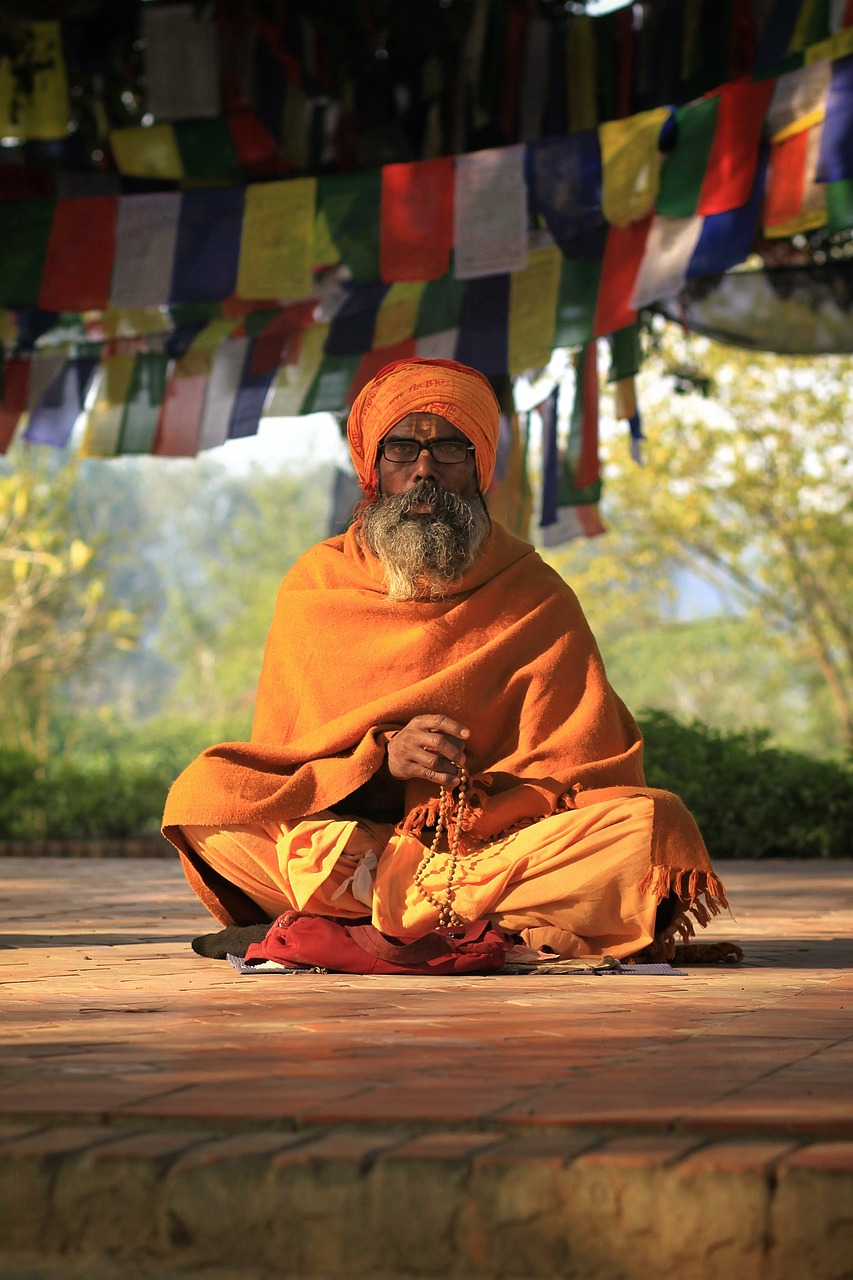 Monk in orange robes meditating with prayer beads at Mulbekh Monastery