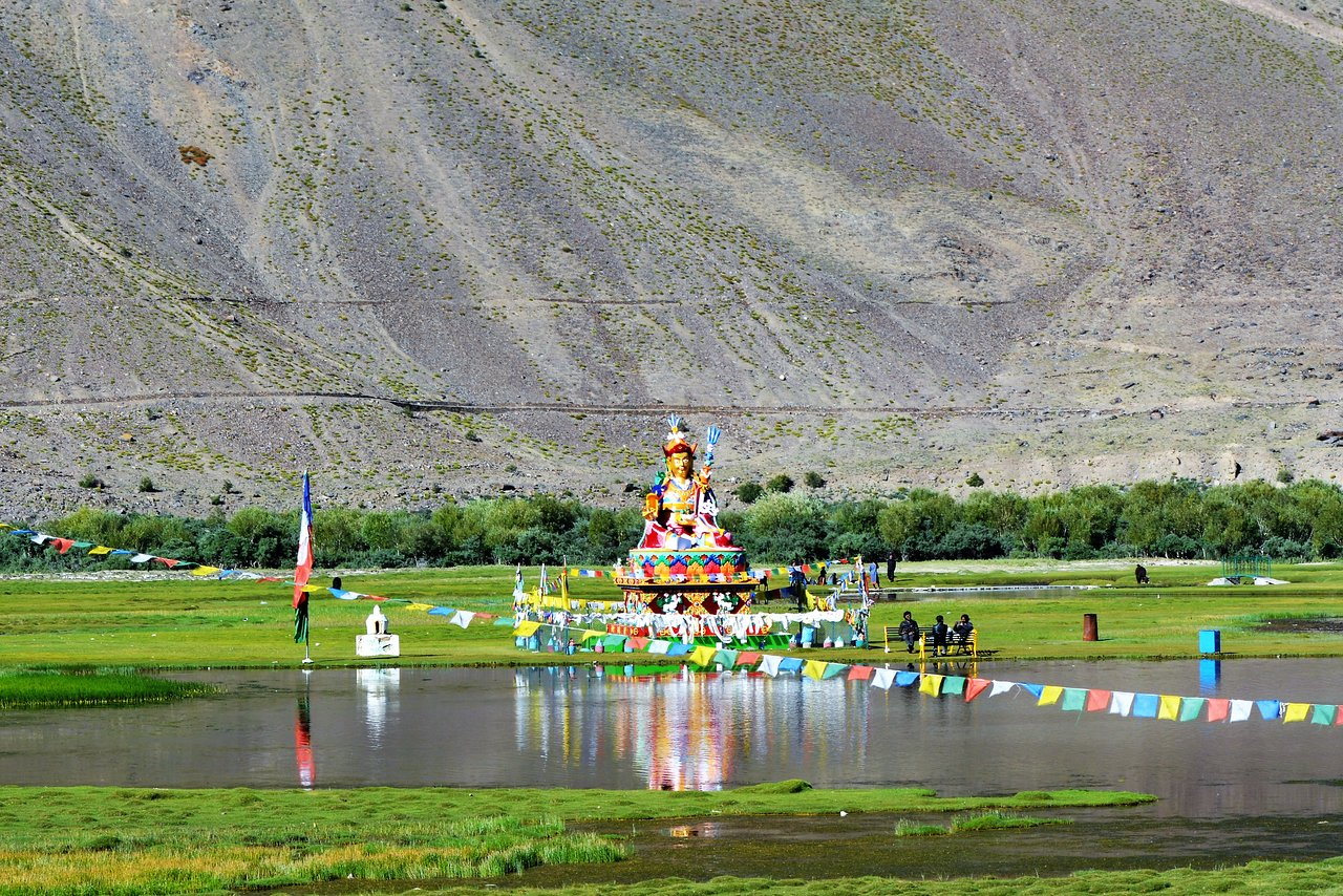 Statue of Guru Padmasambhava at Sani Gompa with prayer flags and pond