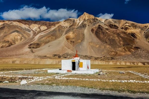 Small white temple in Hunderman village with dramatic brown mountains in the background