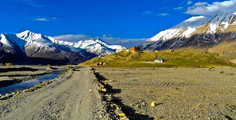 Road to Panikhar village with snowy mountains in the background.