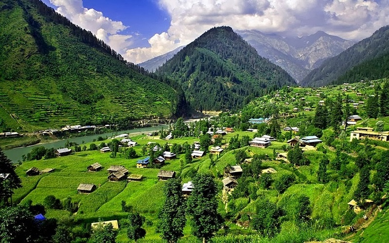Scenic view of a lush green valley in Kashmir with mountains and houses