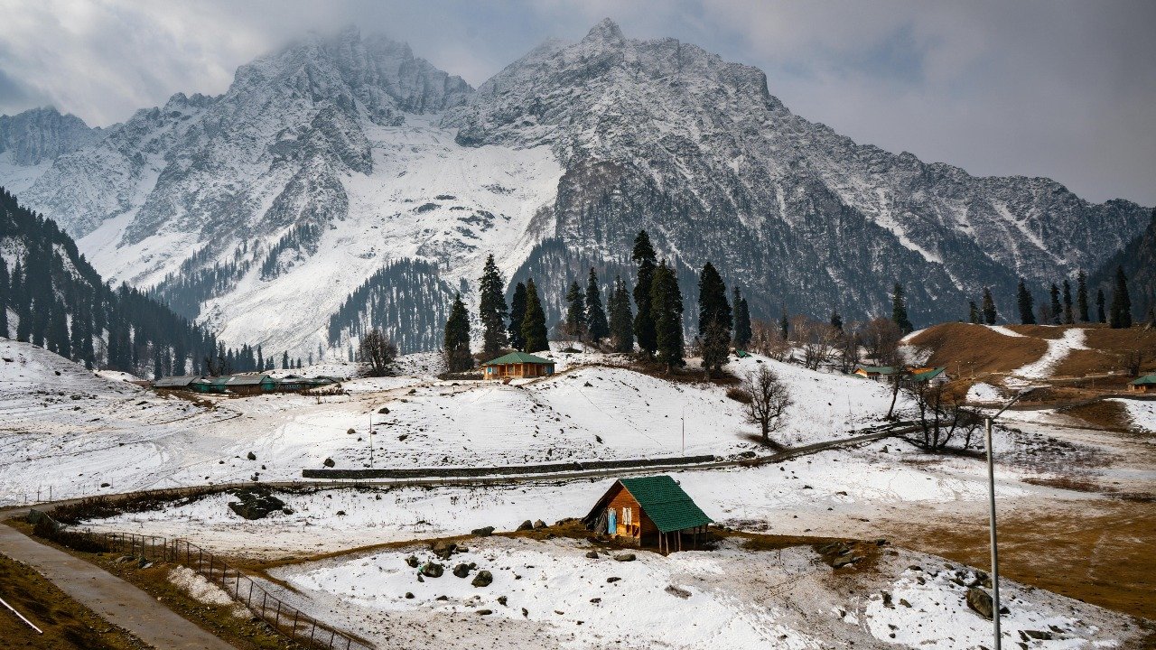 Snow-covered landscape with wooden huts and pine trees at Table Top in Gulmarg.