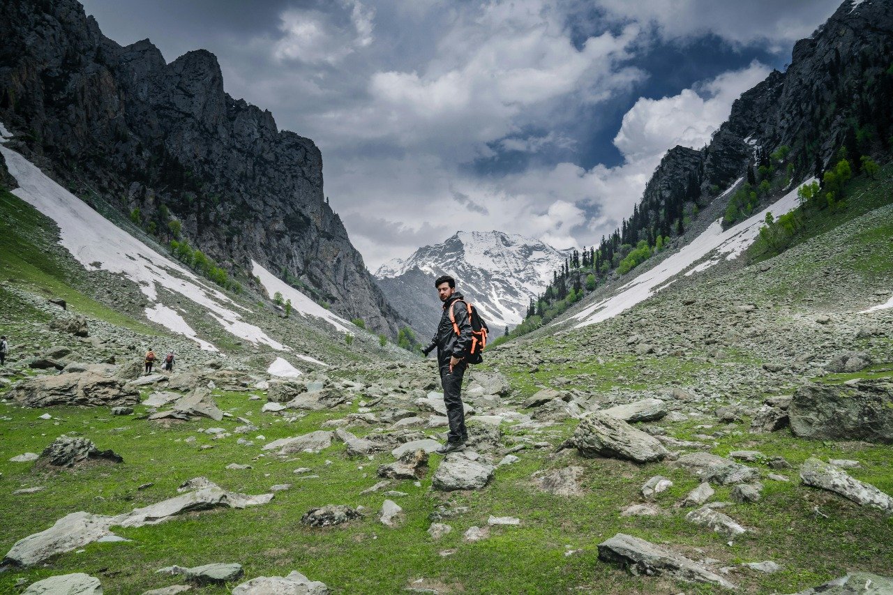 Man trekking through betaab valley with snow-covered mountains in Kashmir
