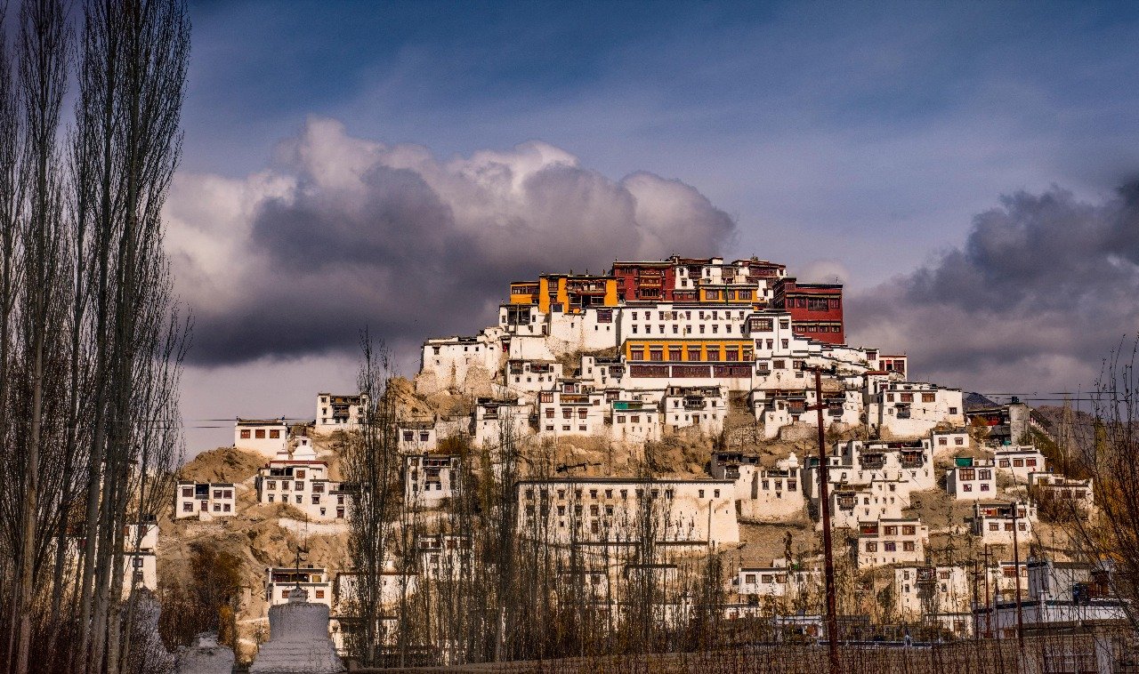 Thiksey Monastery on a hilltop under a dramatic cloudy sky in Ladakh