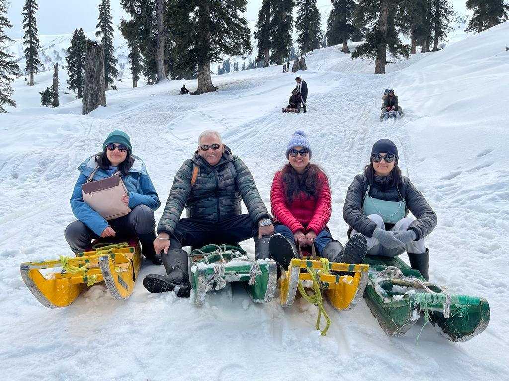 Group of tourists enjoying sledging in the snow-covered hills of Pahalgam